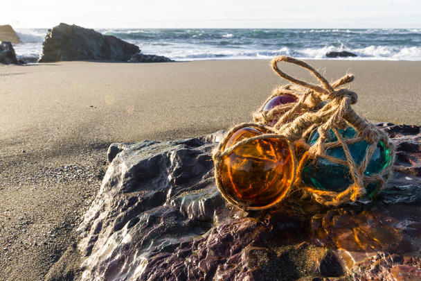 во второй половине дня на побережье Орегона с красочным стеклом плавает на скале и песчаный пляж и океан на заднем плане
 - Фото, изображение