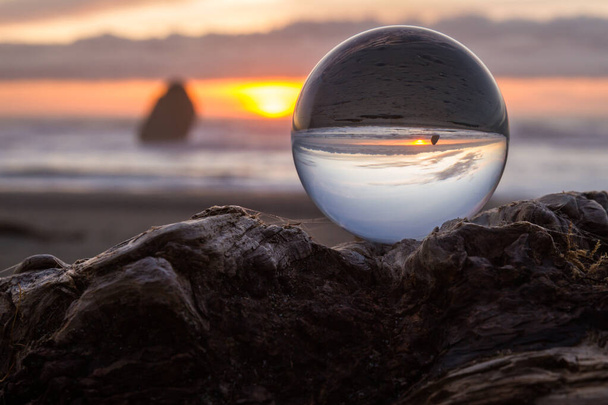 Sahil günbatımı, arka planda bulanık bir görüntü yakalamak için geniş açı mercek kullanarak berrak bir cam küre üzerinde tersine çevrilir. - Fotoğraf, Görsel
