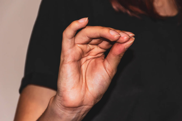 Um close-up de uma mão de uma jovem caucasiana irreconhecível fazendo o gesto italiano
 - Foto, Imagem