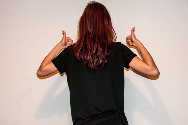 Tanımlanamayan beyaz saçlı genç bir kadının iki eliyle baş parmaklarını gösteren yakın çekim bir stüdyo fotoğrafı. - Fotoğraf, Görsel