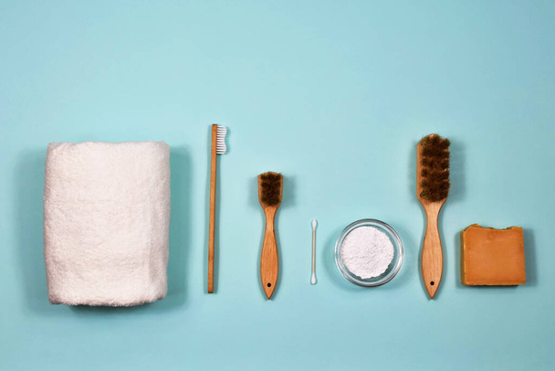 Null-Abfall-Konzept. Zahnbürste, Zahnpuder, Handtuch, Seife und Bürsten auf blauem Hintergrund. Blick von oben. - Foto, Bild