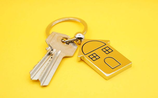 chaveiro com símbolo da casa e chaves no fundo amarelo, conceito imobiliário
      - Foto, Imagem
