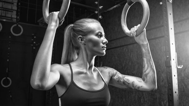 Woman holding gymnastic rings at gym - Foto, imagen