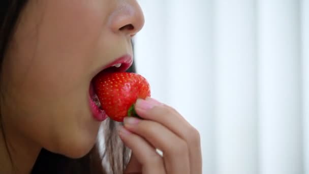 Asian pretty woman holding and eating fresh strawberry is red berry fruit color and sweet juicy with enjoy and happy emotion in concept food, healthy eating in life - Footage, Video