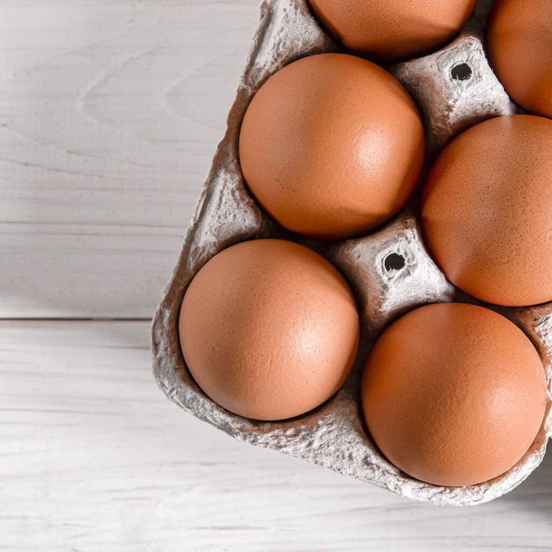 Большие коричневые куриные яйца лежат в экологически чистом картонном подносе для яиц. Крупный план
 - Фото, изображение