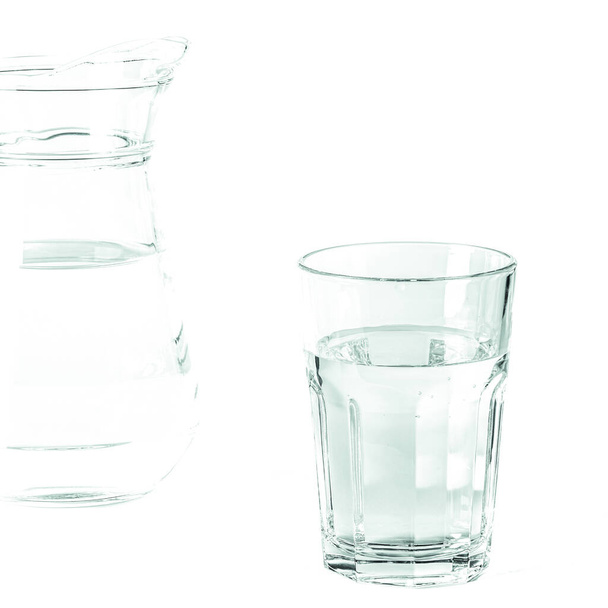 L'acqua limpida pura in un bicchiere e una brocca sta su uno sfondo bianco. isolato - Foto, immagini