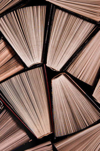 Many open old multicolored books stand on the bookshelf in the library - Foto, Imagem