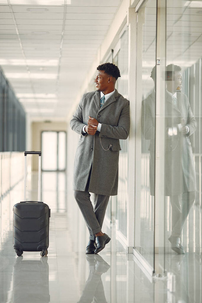 Elegant black man at the airport with a suitcase - Foto, afbeelding