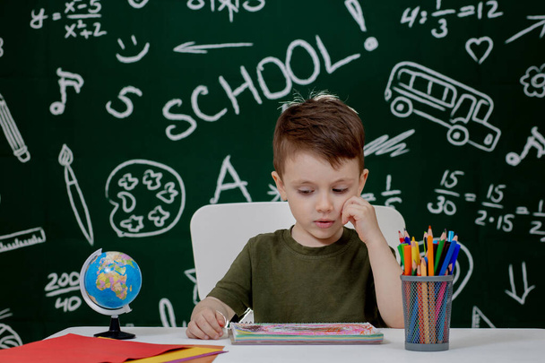 Cute child boy doing homework. Clever kid drawing at desk. Schoolboy. Elementary school student drawing at workplace. Kid enjoy learning. Home schooling. Back to school. Little boy at school lesson. - Foto, Bild