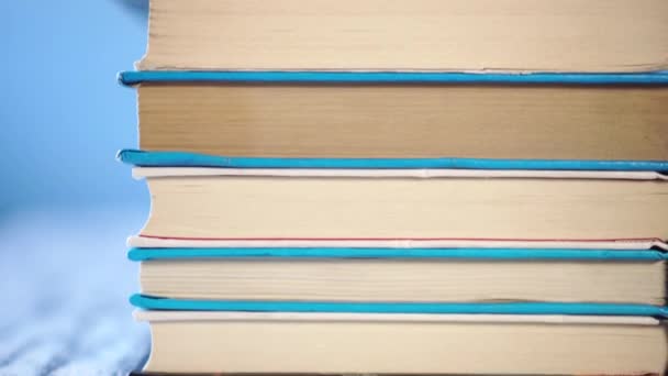 pilha de livros antigos são empilhados em uma mesa de madeira velha. Em um fundo azul brilhante. Close-up. Câmara move-se
 - Filmagem, Vídeo
