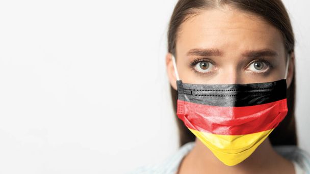 Vrouw in het medische masker met Duitse vlag, Witte achtergrond, Panorama - Foto, afbeelding