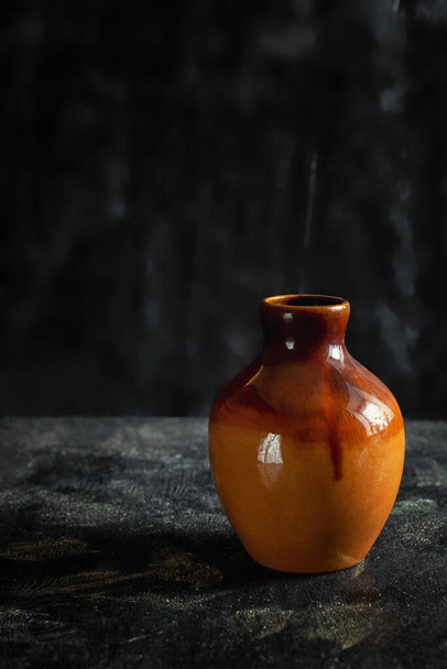 黒い背景のオレンジ粘土の花瓶 - 写真・画像
