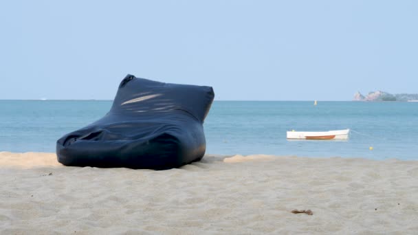 Üres nagy szövet babzsák szék homokos strandon - Felvétel, videó