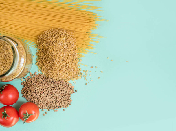 Fresh produce on a light background. Spaghetti, tomato, bulgur, stew, pepper, eco bag. View from above, place for text. - Photo, Image