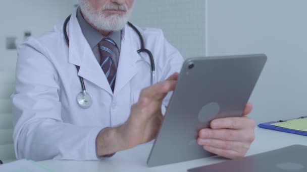 Medical specialist scrolling images on tablet, examining patient's analysis, app - Footage, Video