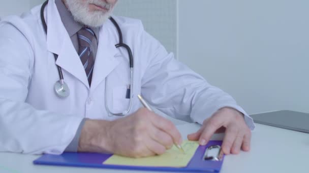 Clinic worker writing prescription, sitting at table, medical treatment, therapy - Video, Çekim
