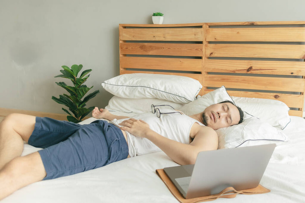 Sleepy lazy man is working from home but sleep in front of the laptop. - 写真・画像