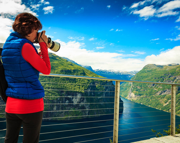 Tourism holidays pictures and traveling. Woman tourist enjoying fjord landscape Geirangerfjord from Ornesvingen viewpoint, taking photo with camera, Norway Scandinavia. - Photo, Image
