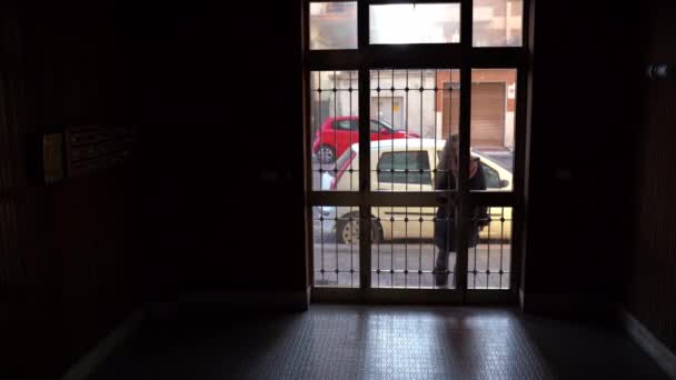 Silhouette eines jungen attraktiven Mädchens, das eine Eisentür mit Schlüsseln öffnet und in den Flur eines dunklen modernen Wohnhauses eintritt. Innenraum des Flureingangs - Filmmaterial, Video