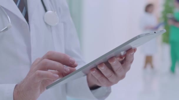Male doctor scrolling tablet, checking analysis online, searching information - Video, Çekim