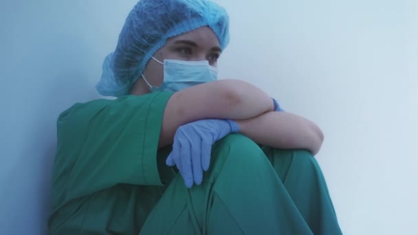 Sad doctor in protective mask and gloves sitting on the floor in hospital, job - Filmagem, Vídeo