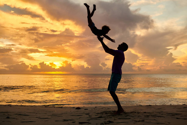 Счастливое дитя, отец подбрасывает сына в воздух. Трехлетний мальчик на пляже с отцом на закате. Летний семейный отдых на Сейшельских островах
. - Фото, изображение