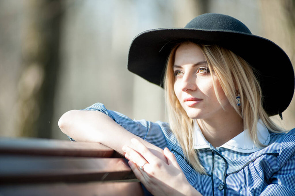 close up portrait of young blond woman sitting on bench on park background - Фото, зображення