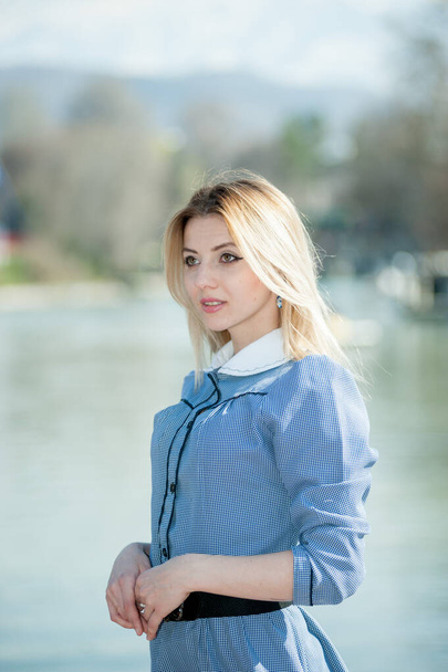 young blond woman in blue dress posing on park background - Fotoğraf, Görsel