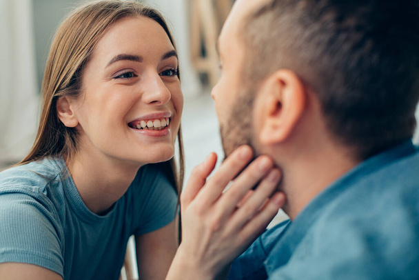 Excited young woman smiling happily and touching a cheek of her boyfriend stock photo - Photo, Image