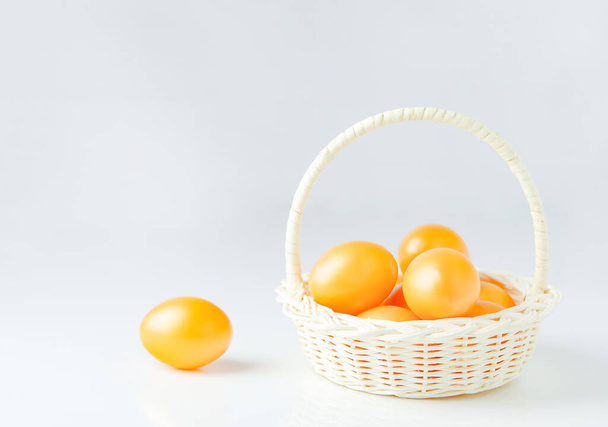 Primer plano de huevos de Pascua dorados en canasta blanca sobre fondo blanco
 - Foto, Imagen