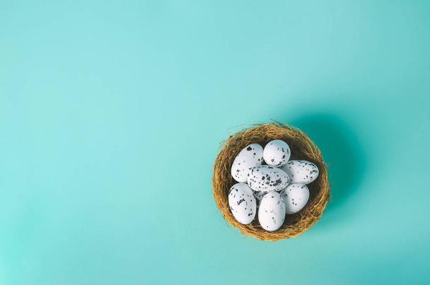Small artificial eggs with nest on light blue background with vintage tone, Easter egg background - Foto, Imagem