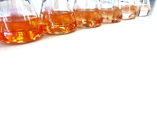 Erlenmeyerin tai erlenmeyerin pullo penkkilaboratoriossa, jossa on kaltevuusliuotin analyysipitoisuusaluetta varten, näyttää oranssin värin, havaitsee UV-spektrofotometrillä. Valikoiva painopiste
. - Valokuva, kuva