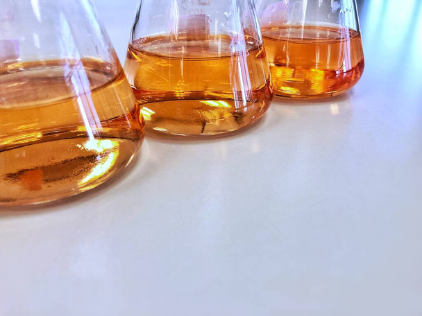 De Erlenmeyer of erlenmeyer op het laboratorium van de bank, met gradiënt oplosmiddel voor analyse concentratiebereik van ijzer tonen de oranje kleur, detecteren met UV-spectrofotometer. Selectieve focus. - Foto, afbeelding