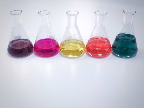 ベンチ実験室に並ぶErlenmeyerまたはConicalフラスコには、滴定実験、酸度、アルカリ性、排水サンプルの総硬度分析などのカラフルな溶剤が含まれています。コピースペースあり. - 写真・画像