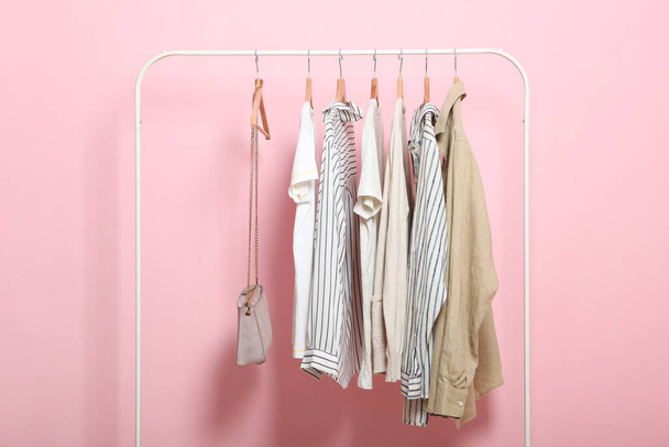 fashionable clothes on hangers on a wardrobe rack on a colored background. - Foto, Bild