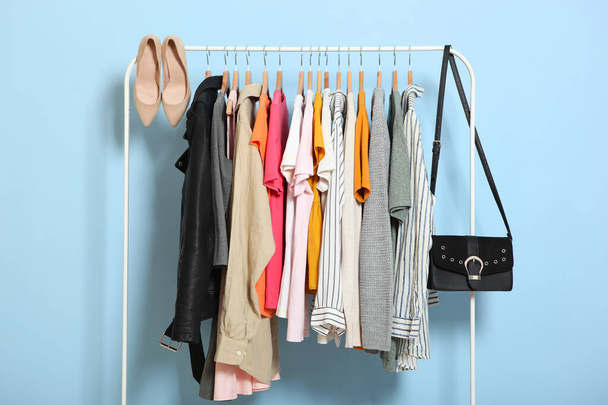 μοντέρνα ρούχα σε κρεμάστρες σε ένα ράφι ντουλάπα σε ένα έγχρωμο φόντο. - Φωτογραφία, εικόνα