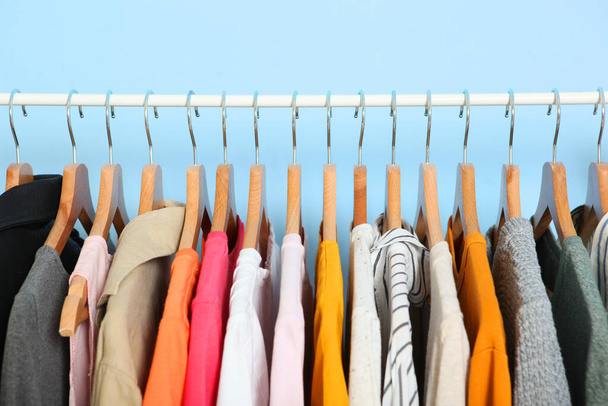 modieuze kleding op hangers op een kledingrek op een gekleurde achtergrond. - Foto, afbeelding