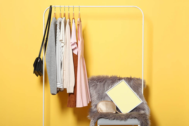 μοντέρνα ρούχα σε κρεμάστρες σε ένα ράφι ντουλάπα σε ένα έγχρωμο φόντο. - Φωτογραφία, εικόνα