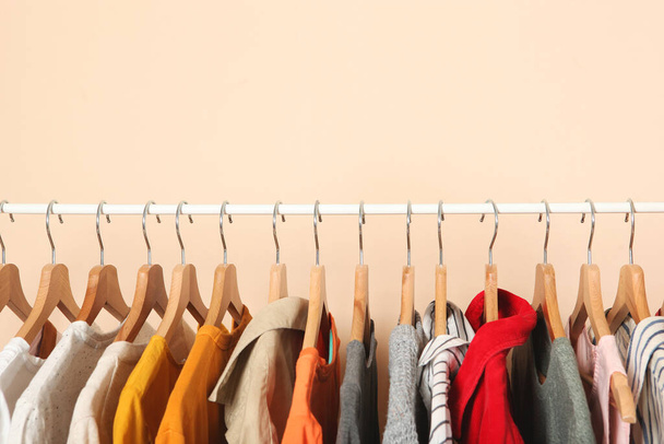 fashionable clothes on hangers on a wardrobe rack on a colored background. - Zdjęcie, obraz