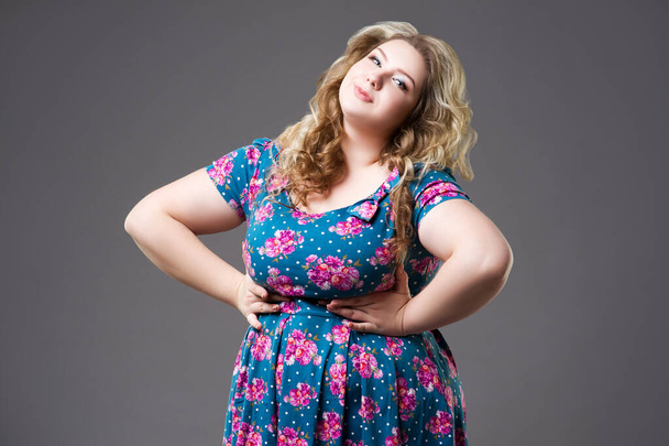 Plus size fashion model in floral dress, fat woman on gray background, body positive concept - Foto, imagen