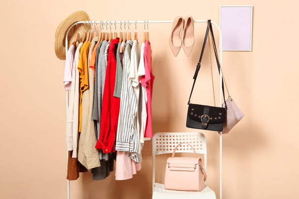 La ropa a la moda en las perchas en el armario-estante sobre el fondo de color
. - Foto, imagen