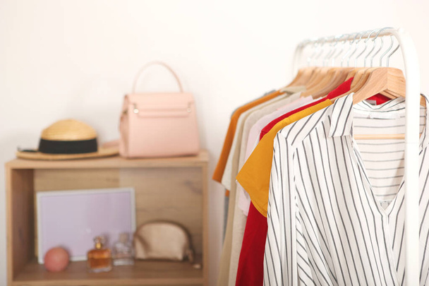 Modische Kleidung auf Kleiderbügeln auf einem Kleiderständer im Hintergrund des Zimmers. - Foto, Bild