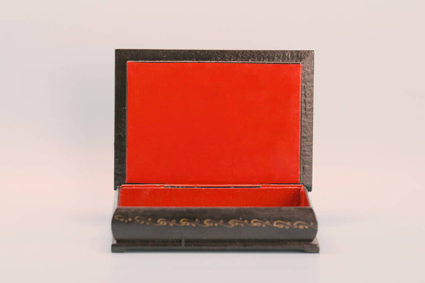 Black with gold painted empty lacquered wooden casket stands open. Inside is red - Foto, Bild