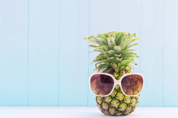 Funny Pineapple with white sunglasses on blue wooden background, Tropical and summer fruit - Foto, immagini