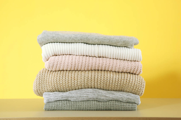 een stapel warme truien op tafel op een gekleurde achtergrond. - Foto, afbeelding