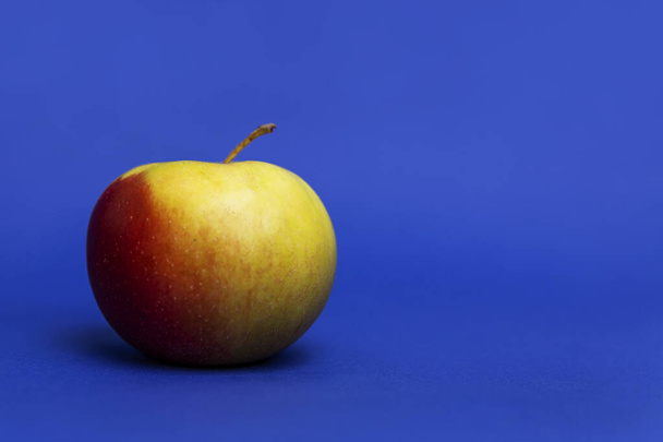 Juicy red apple. Blue background. Healthy diet and vegan nutrition. Close-up. - Foto, afbeelding