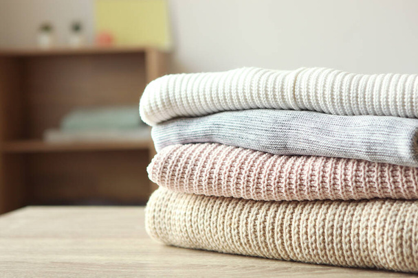 a stack of warm sweaters on the table on a light background. - Φωτογραφία, εικόνα