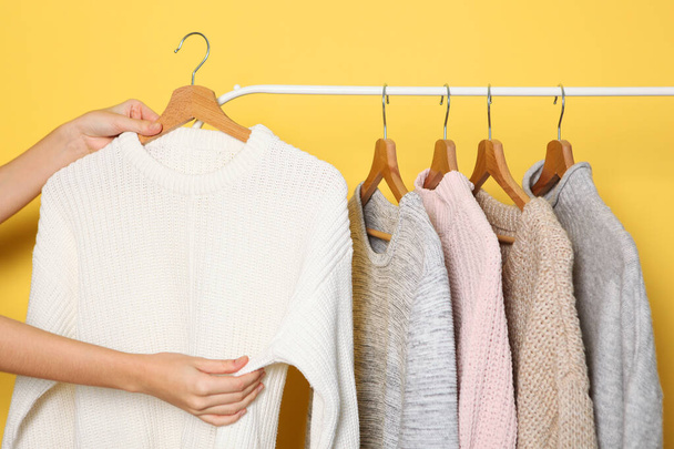 Girl chooses a warm sweater from the wardrobe of the hanger. - Foto, Imagen