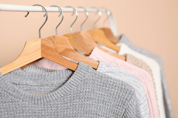 Suéteres calientes en una percha de armario sobre un fondo de color. Otoño, ropa de invierno. - Foto, imagen