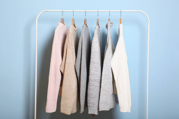 Suéteres calientes en una percha de armario sobre un fondo de color. Otoño, ropa de invierno. - Foto, Imagen